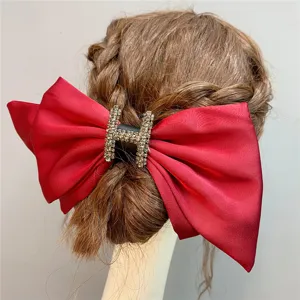 Red satin hair bow clip with rhinestone H metal buckle, elegant wedding headwear accessory.