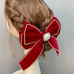 Red velvet hair bow clip with rhinestones and pearl center, elegant bridal wedding headwear accessory.