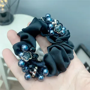Elegant black fabric hair scrunchie with blue pearls and sparkling flower charms.