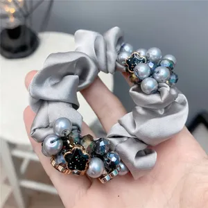 Grey satin scrunchie detail with pearls and crystals, elegant hair accessory close up.