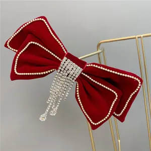 Red velvet bow hair clip with sparkling rhinestones and tassel details for wedding bridal wear.
