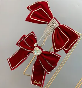 Red velvet bow hair clip with sparkling rhinestones and crystal pendant for bridal wedding wear.