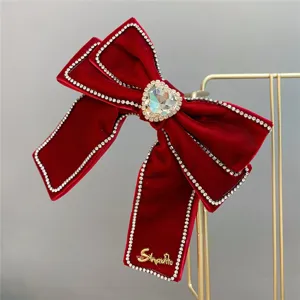 Red velvet bow hair clip with crystal rhinestones and heart centerpiece for festive wedding wear.
