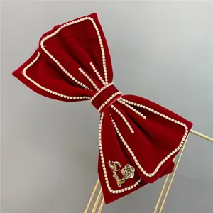 Red velvet bow hair clip with rhinestone trim and metal rose detail for special occasions