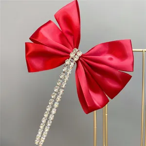 Red velvet bow hair clip featuring stunning rhinestone tassel chains for elegant bridal wear.
