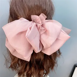 Detail view of the oversized pink mesh hair bow with layered draping spring clip design.