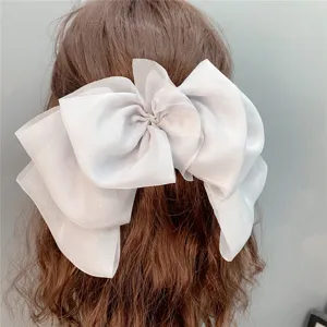 Detailed view of the large grey organza hair bow clip, showing layered sheer mesh texture.
