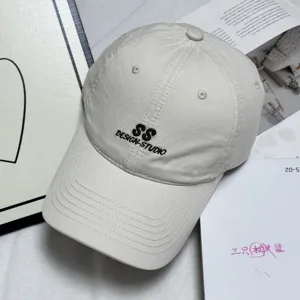 Detail view of beige washed cotton baseball cap with stylish front letter embroidery.