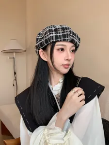 Dettaglio berretto classico a quadri nero e bianco con logo V in metallo, cappello autunnale.