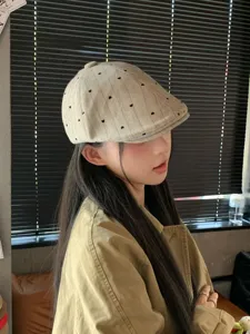 Detail shot of the Japanese retro heart embroidered newsboy cap worn by model indoors.