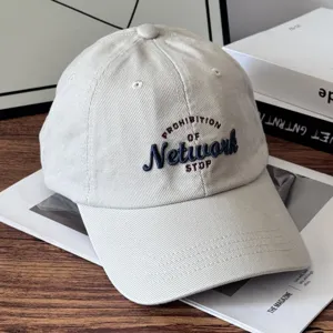 Detail shot of vintage beige baseball cap with stylish embroidered text and premium cotton fabric.