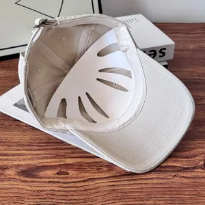 Detail view of beige cotton baseball cap showing interior structure and metal buckle.