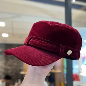 Wijnrode corduroy platte pet voor dames, vintage hoed met zachte textuur en metalen knop.