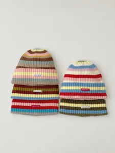 Detailed view of colorful striped knitted beanies with small brand patches for autumn.