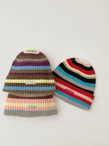 Colorful striped knit beanie detail, cozy winter woolen hat with letter woven label closeup.