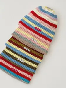 Close-up detail of colorful striped knit beanies with small brand labels, soft autumn style.
