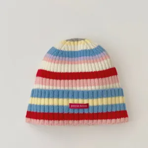 Close-up detail of colorful striped knit beanie with small brand label, cozy winter warm hat.