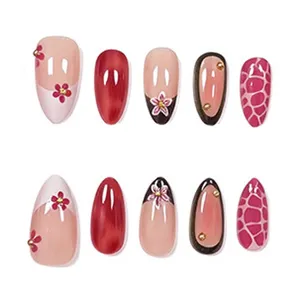 Gros plan détaillé de faux ongles amande ornés d'un art floral français délicat et de tons roses chics.