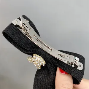 Black knit bow hair clip with rhinestone rabbit charm, detailed view showing metal spring clip.