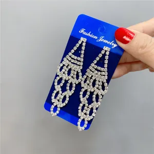 Long rhinestone tassel earrings with sparkling crystals on a blue display card detail shot.