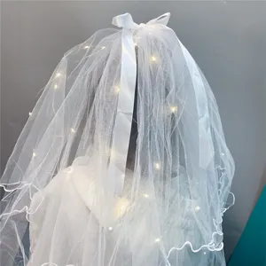 Detail shot of white kids veil featuring double mesh layers, pearls, and fairy lights.