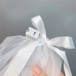 White bridal veil mesh material detail close up showcasing elegant satin bow and battery box.