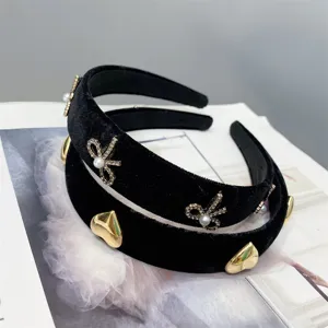 Black velvet padded headband detail featuring metallic gold hearts and crystal pearl bow accessories.