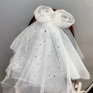 Close-up detail of the elegant white mesh hair bow with sparkling rhinestones and sequins.