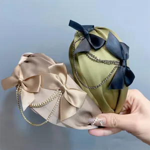 Elegant satin headband featuring sweet bows and sparkling rhinestone chain detail.