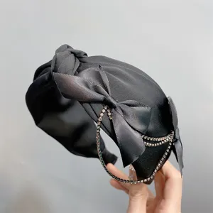 Black satin knotted headband with bow and rhinestone fringe details for women fashion.
