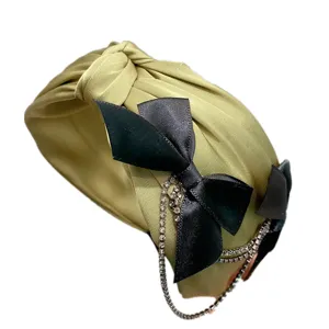 Green satin knotted headband featuring black bow and rhinestone tassel chains, sweet hair accessory.