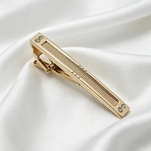 Élégante pince à cravate dorée pour homme avec incrustation texturée et strass étincelants.