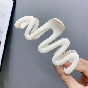 Close-up detail of cream white wavy hair claw clip, elegant design for styling hair.