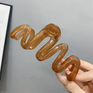 Detailed view of a trendy translucent brown wavy hair claw clip, perfect for stylish updos.
