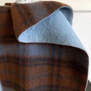 Close-up view of a thick woolen plaid scarf, showing soft blue and brown checkered texture.