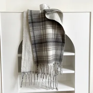 Detailed view of grey and white plaid winter scarf with fringe design showcasing soft fabric texture.