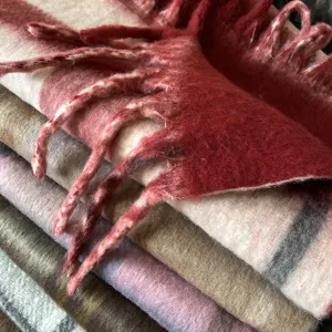 Close-up detail of cozy thickened plaid winter scarf with soft fringe and warm texture.