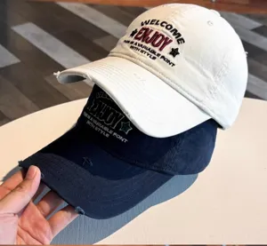 Primer plano detalle gorra de béisbol ENJOY bordada, visera rota, corona suave, estilo urbano.