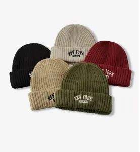 Primer plano de elegantes gorros de punto con bordado New York en varios colores.
