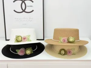 Eleganter flacher Strohhut mit Blumen und Perlen Dekor für den sommerlichen Strand.
