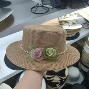 Detailansicht eines stilvollen flachen Strohhutes mit Perlen und Rosen für den Sommer.