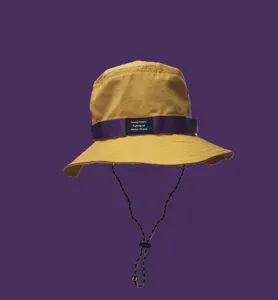 Gros plan sur le bob jaune avec sa sangle violette et sa cordelette de vent réglable.
