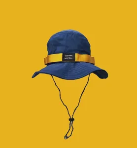 Vue détaillée du chapeau bachois bleu avec sangle jaune, corde vent et étiquette noire.