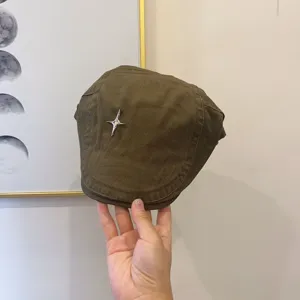 Detailansicht der dunkelgrünen Schiebermütze mit einem metallischen vierzackigen Stern.