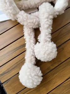 Détail bonnet hiver peluche avec rabats d'oreilles, polaire douce et pompons mignons.