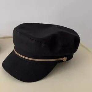 Schwarze Retro Damen Schiebermütze Detailaufnahme, flache Mütze mit goldener Kordel.