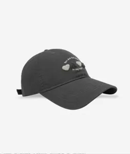 Detail shot of a dark grey baseball cap featuring cute fuzzy heart embroidery and sweet text.