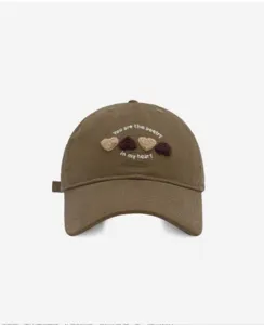 Detail view of the brown cotton baseball cap featuring cute embroidered hearts and sweet text.