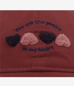 Close-up detail of cute embroidered heart baseball cap featuring stylish quote embroidery.