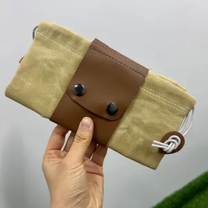 Détail de sac de cueillette en toile, rabat en cuir PU marron avec boutons et cordon.